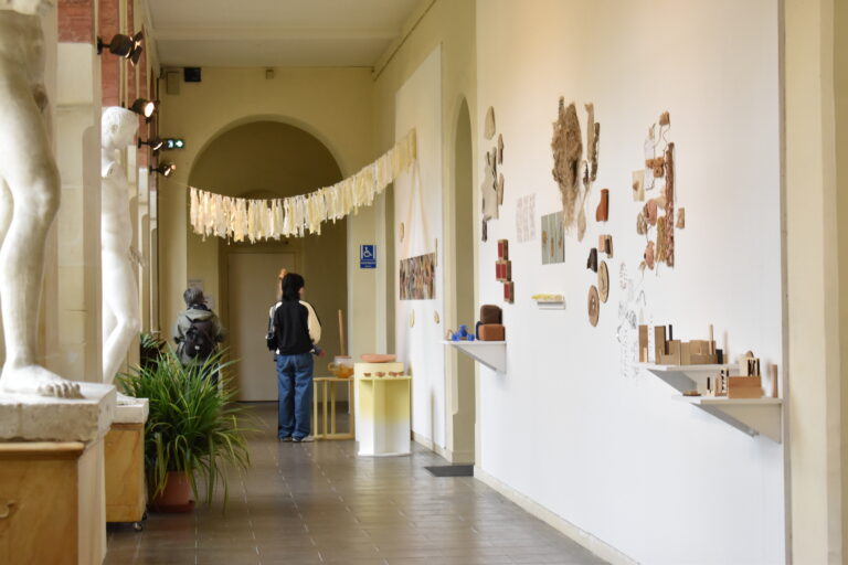 vue d'un couloir avec des statues d'un côté, un mur d'exposition de l'autre