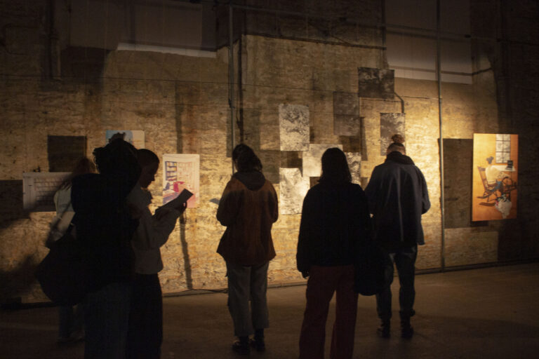 Des personnes dans un lieu sombre regardent des oeuvres éclairées
