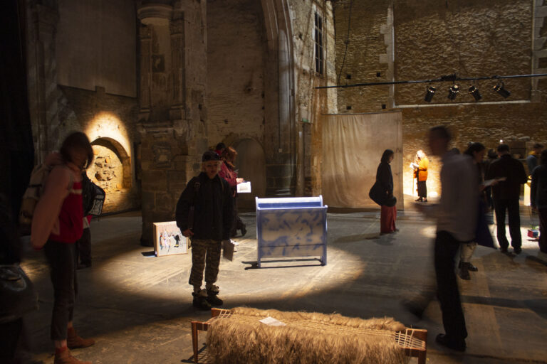 Des personnes dans un lieu sombre regardent des oeuvres éclairées